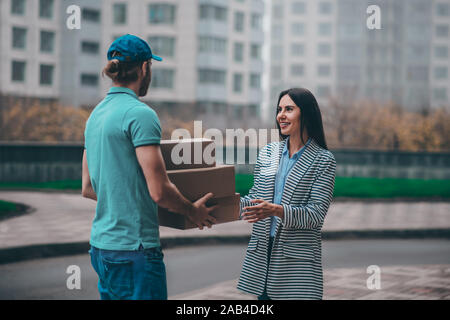 Geschäftsfrau tragen Jacke Sitzung Delivery Man außerhalb Stockfoto