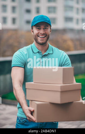 Positive Lieferung Mann mit t-shirt Holding boxen für Clients Stockfoto