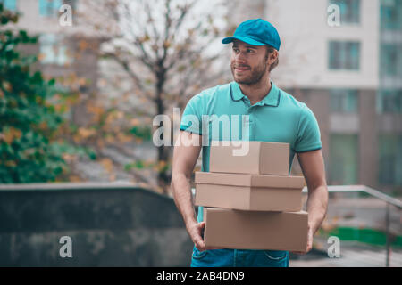 Schöne bärtige Lieferung Mann mit t-shirt Holding boxen Stockfoto
