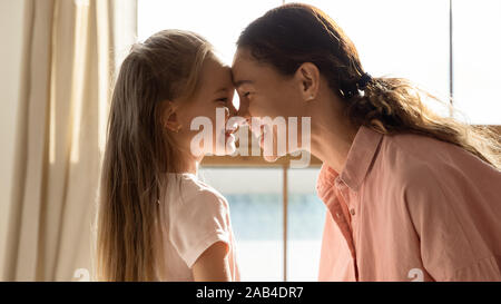 Fröhliche Mutter und niedlichen Tochter berühren Nasen im sonnigen Zimmer Stockfoto