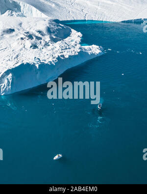 Buckelwal Tauchen in der Nähe von kleinen Boot, Schiff, Boot, auf dem Tauchgang. Eisberge mit blauen Wasser des Ozeans. Grönland Disko Bay Area in der Nähe von Ilulissat Stockfoto