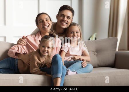 Lächelnd Eltern umarmen kleine Kinder Töchter entspannt auf der Couch, Porträt Stockfoto