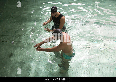 Mann, Schwimmunterricht mit einem Lehrer. Stockfoto