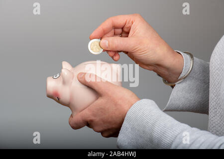 Frau, eine Münze in ein Sparschwein Stockfoto