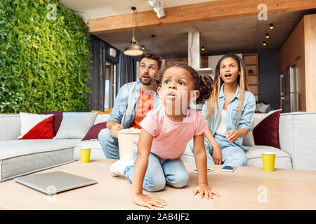 Familie Fernsehen, aufgeregt, Gesichter und zu Hause ausruhen Stockfoto