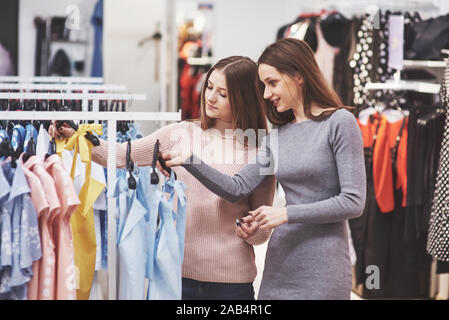 Die besten Freunde zusammen Zeit verbringen. Zwei hübsche Mädchen Einkäufe in das Bekleidungsgeschäft. Sie gekleidet in der gleichen Kleidung Stockfoto