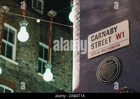 London, Großbritannien, 17. November 2019: Lord John gedenktafel und Straßennamen Zeichen an der Wand in der Carnaby Street, London, Fußgängerzone und Einkaufsstraße in Stockfoto