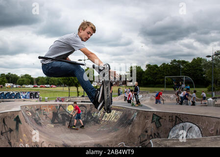 Einer der britischen Top roller Rider Josh Glas üben an der lokalen Skatepark, Stunts auf der ganzen Skatepark mit Menschen beobachten auf Stockfoto