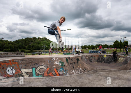 Einer der britischen Top roller Rider Josh Glas üben an der lokalen Skatepark, Stunts auf der ganzen Skatepark mit Menschen beobachten auf Stockfoto