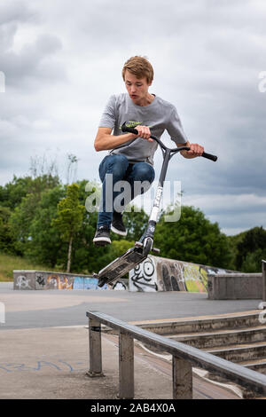 Einer der britischen Top roller Rider Josh Glas üben an der lokalen Skatepark, Stunts auf der ganzen Skatepark mit Menschen beobachten auf Stockfoto