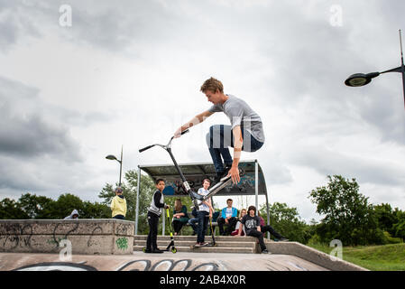 Einer der britischen Top roller Rider Josh Glas üben an der lokalen Skatepark, Stunts auf der ganzen Skatepark mit Menschen beobachten auf Stockfoto