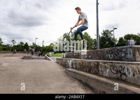 Einer der britischen Top roller Rider Josh Glas üben an der lokalen Skatepark, Stunts auf der ganzen Skatepark mit Menschen beobachten auf Stockfoto