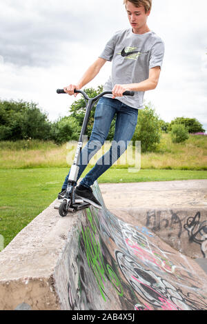 Einer der britischen Top roller Rider Josh Glas üben an der lokalen Skatepark, Stunts auf der ganzen Skatepark mit Menschen beobachten auf Stockfoto