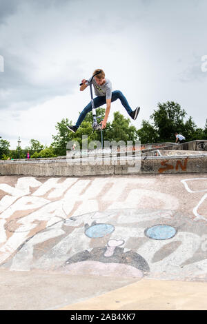 Einer der britischen Top roller Rider Josh Glas üben an der lokalen Skatepark, Stunts auf der ganzen Skatepark mit Menschen beobachten auf Stockfoto