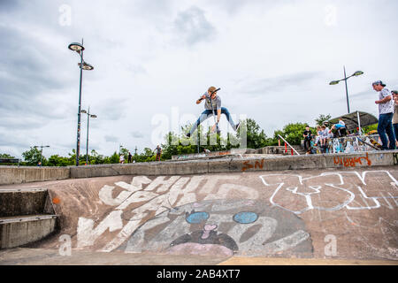 Einer der britischen Top roller Rider Josh Glas üben an der lokalen Skatepark, Stunts auf der ganzen Skatepark mit Menschen beobachten auf Stockfoto