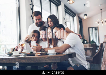Eine Gruppe von Menschen einen selfie Foto in einem Café. Die besten Freunde versammelt, zusammen an einem Tisch essen Pizza und Singen verschiedene Getränke Stockfoto