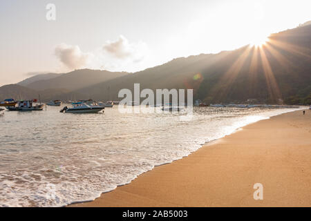 Ilha Grande, Brasilien. 24. Dezember, 2012. Taxi, Boote, Boote und Segel Boote in der Bucht vor Anker aus Sandstrand mit Sonnenstrahlen, die durch die Berge, während der Morgen im Vila tun sehen Santorini Santorini (Dorf), Ilha Grande, die Gemeinde von Angra dos Reis, Bundesstaat Rio de Janeiro, Brasilien. Am 5. Juli 2019, Ilha Grande wurde von der UNESCO als Weltkulturerbe eingetragen. Stockfoto