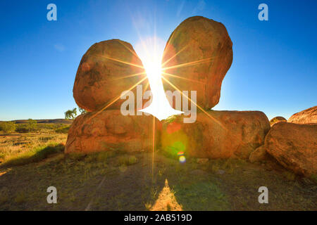 Australien, Northern Territory. Land der Aborigines im Roten Zentrum. Sonnenstrahlen Himmel bei Sonnenaufgang hinter iconic die Eier der mythischen Rainbow Serpent Karlu Stockfoto