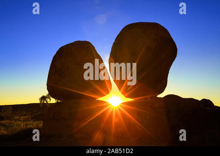 Sonnenstrahlen in der Dämmerung hinter iconic Devils Marbles: Eier von mythischen Regenbogenschlange. Karlu Karlu Devils Marbles Conservation Reserve ist einer von Australiens Stockfoto