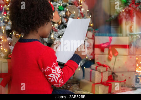 Die Vorbereitung auf Weihnachten. Kleine schwarze Mädchen, dass leere Blatt Papier Stockfoto