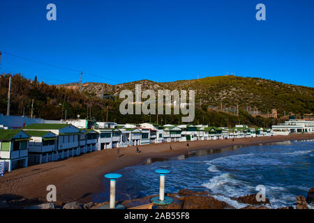 Platja de Les Casetes del Garraf, Garraf, Barcelona, Katalonien. Die markanten kleinen grünen und weißen Strand Häuser sind im Beach Village von Garra Stockfoto