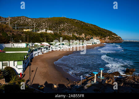 Platja de Les Casetes del Garraf, Garraf, Barcelona, Katalonien. Die markanten kleinen grünen und weißen Strand Häuser sind im Beach Village von Garra Stockfoto