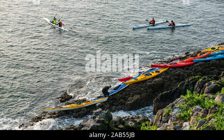 Lothian Sea Kayak Club Kajaks auf felsigen Ufer mit Kajakfahrer in Wasser, Lamm Insel, Erhabene, Schottland, Großbritannien Stockfoto