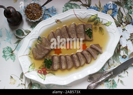 Aspic der Zunge verziert mit gekochten Karotten und Petersilie auf einem festlichen Hintergrund. Rustikaler Stil. Stockfoto