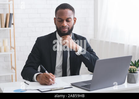 Ernsthafte junge Manager Signieren von Dokumenten in seinem Büro Stockfoto