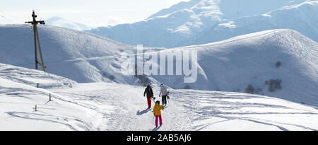 Skifahrer und Snowboarder auf Schnee Straße bei Sun winter Morgen. Kaukasus, Georgien, Region Gudauri. Panoramablick. Stockfoto