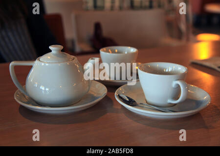 Tee für zwei. Сeramic Teekanne und Tassen (Schalen) mit duftenden heißen Tee auf verschwommenen Hintergrund. Festliche des Neuen Jahres Tabelle in einem kleinen Café Stockfoto