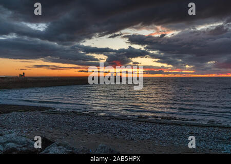 Der North Pier Leuchtturm mit einigen dunklen Wolken nach Sonnenuntergang im Whitehaven, Cumbria, England, Großbritannien Stockfoto