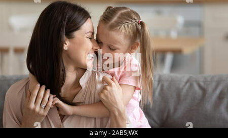 Süße kleine Tochter hug Pflege junge Mama kuscheln auf der Couch Stockfoto