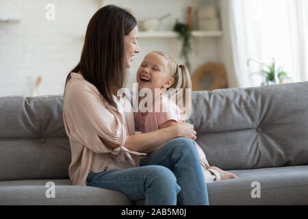 Fröhliche Mama spielen Lachen mit entzückenden kleinen Tochter auf dem Sofa Stockfoto