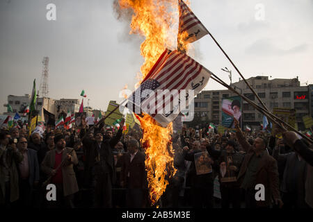 Teheran, Iran. 25 Nov, 2019. Iraner brennen uns Flaggen bei einer Rallye ihre Unterstützung der Islamischen Republik System zu zeigen und die jüngsten gewaltsamen Protesten zu folgenden Kraftstoffpreis Wanderung im Land zu verurteilen, an Enghelab Square im Zentrum von Teheran, Iran. In einem Schock Ankündigung vor zehn Tagen hatte der Iran der Benzinpreise um bis zu 200 Prozent angehoben, Auslösen von landesweiten Protesten in einem Land, dessen Wirtschaft zerschlagen worden ist von den US-Sanktionen. Credit: rouzbeh Fouladi/ZUMA Draht/Alamy leben Nachrichten Stockfoto