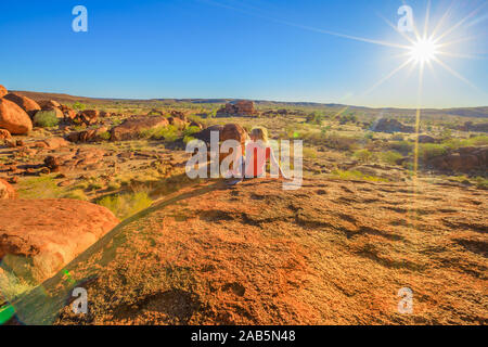 Touristische Frau auf der Oberseite von Karlu Karlu Devils Marbles Conservation Reserve Blick auf Granitfelsen Felsformationen bei Sonnenuntergang mit der Suche Stockfoto