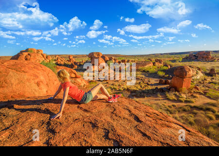 Touristische Frau auf Nyanjiki Lookout bei Sonnenuntergang bewundern Panoramablick und lebendige Farben von riesigen Felsbrocken der natürlichen Felsformationen bei Karlu Karlu Stockfoto