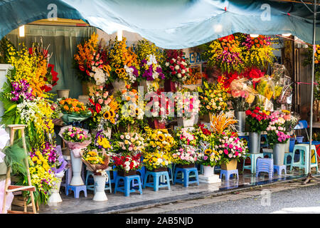 Trauben, die von leuchtenden Blumen Blumensträuße auf Anzeige außen ein Shop in Hanoi, Vietnam, Asien Stockfoto