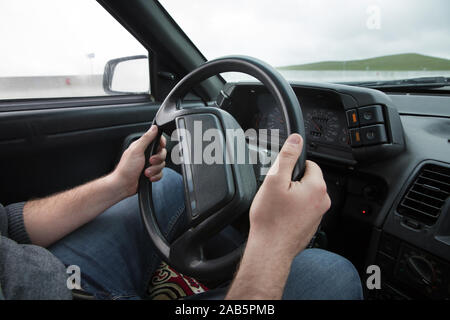 Innenraum. Männliche Arme ledernen Ruder des Autos. Der Mann packt das Lenkrad und fährt das Auto. Schwarze Bedienfeld in einem alten russischen Auto Stockfoto