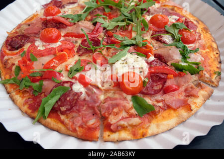 Pizza auf weißem Papier. Lecker lecker Pizza in Stücke schneiden mit Salami, Mozzarella, rote Tomaten und Rucola. Fast food im verfügbaren di Stockfoto