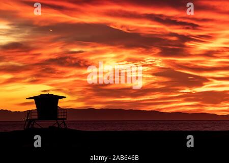 Helles orange dramatischer Sonnenuntergang mit Lifeguard tower Silhouette Stockfoto