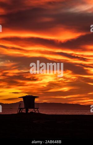 Helles orange dramatischer Sonnenuntergang mit Lifeguard tower Silhouette Stockfoto