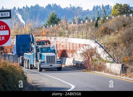 Mobile Big Rig Abschleppwagen mit Anheben des Auslegers und drei fahren Lkw Hinterachsen abschleppen gebrochen Blue Big Rig Semi Truck Traktor mit Notbeleuchtung auf t Stockfoto