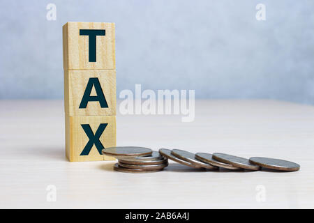 Steuerkonzept mit Holzklotz auf Gestapelte Münzen Stockfoto