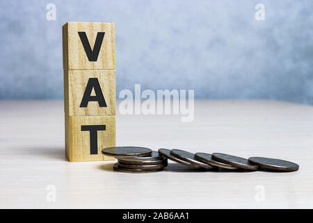 Mwst. Konzept mit Holzklotz auf Gestapelte Münzen Stockfoto