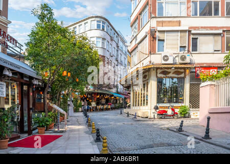 Eine Straße mit Cafés und Geschäften mit einem Motorroller in einem touristischen Abschnitt von Sultanahmet in Istanbul, Türkei Stockfoto