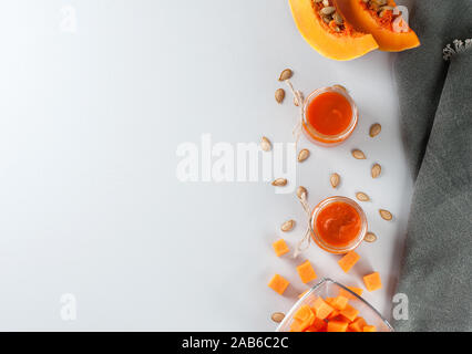 Frische Kürbis Marmelade in Gläser auf dem grauen Hintergrund mit Kürbiskernen verziert. Herbst Rezepte aus einem Kürbis. Gesunde Ernährung Konzept. Flach, horizo Stockfoto