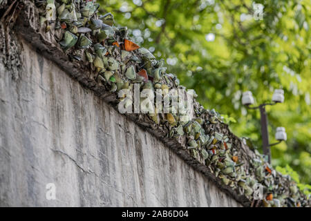 Zerschlagene Glasflaschen sind oben an einer Wand zu Gefangenen die Flucht aus der Hanoi Hotel politische Gefängnis in Vietnam verhindern klemmt Stockfoto