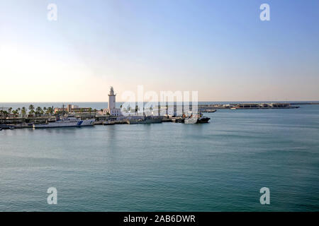 Der Hafen von Malaga, mit einigen kleinen Schiffen angedockt und den Leuchtturm auf der Mole, Andalusien, Südspanien. Stockfoto