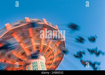 Vergnügungspark Bewegung verwischt Karussell Mitfahrer auf der Retro Vintage kippen Schwingen gegen den klaren blauen Himmel. Stockfoto